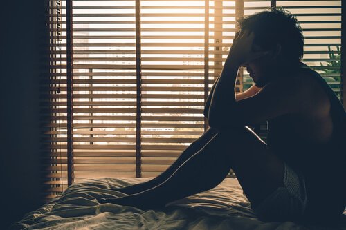 남성 성기능 장애: 어두운 방 침대 위에 고민하는 남자 사진