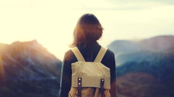 백팩을 메고 하늘을 보고 있는 여자의 뒷모습 사진
