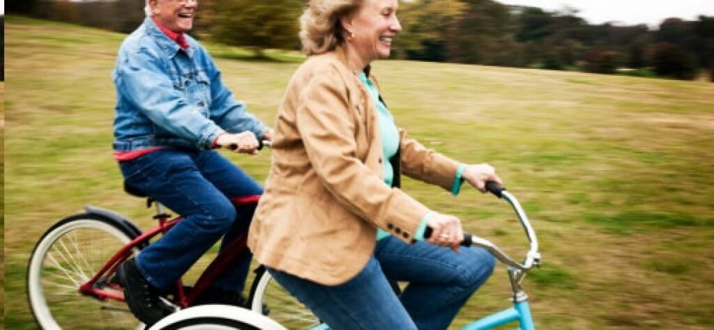 자전거를 타며 웃고 있는 두 나이든 커플 사진