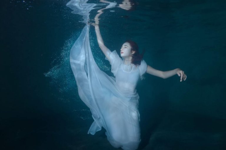 하얀 드레스를 입고 물에 잠긴 여자 사진